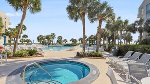 A pool area with lounge chairs and palm trees.