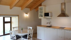 Une cuisine moderne avec des meubles blancs, un plafond en bois et un four à micro-ondes encastré.