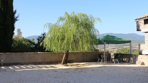 Un espace patio agrémenté d’un auvent végétal, de sièges d’extérieur et offrant une vue sur les montagnes lointaines.