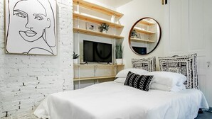 A bedroom with a bed, a TV, a mirror, and a white brick wall. - Dupont Circle sub station DC Apart High speed WiFi (Washington)