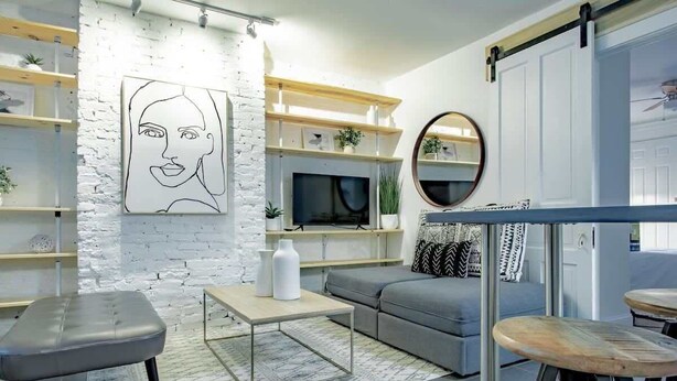 A modern living room with a white brick wall, a mounted TV, and a grey sofa. - Dupont Circle sub station DC Apart High speed WiFi (Washington)