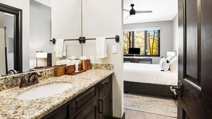 Ein modernes Badezimmer mit einer Granittheke, dunklen Holzschränken und einem großen Spiegel.