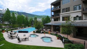Ein Resort mit großem Schwimmbecken, Sitzgelegenheiten im Freien und Blick auf die Berge.