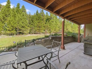 An outdoor patio with a table and chairs, a barbecue grill, and a stone wall with plants. - Swans Nest Villa 1304 2 Bedroom Condo by RedAwning (Breckenridge)