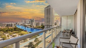 Ein Balkon mit Blick auf die Stadt, ein Pool und Sitzmöglichkeiten im Freien.