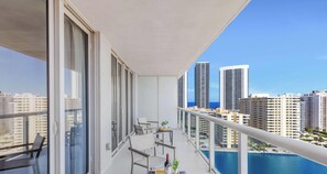 Uma varanda com mesa, cadeiras e vista para prédios altos.