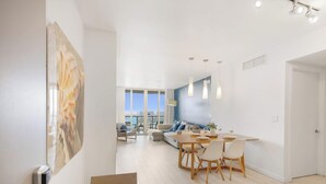 Una sala de estar moderna con comedor, ventanas amplias y vista a la ciudad.