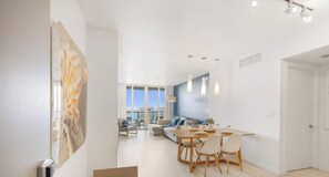 Un salon moderne avec un coin repas, de grandes fenêtres et une vue sur la ville.