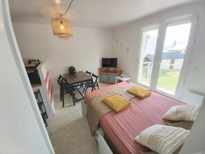 A bedroom with a bed, a desk, a chair, a television, and a window.