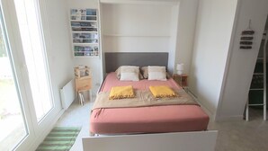 A modern bedroom with a bed, bedside tables, a small desk, and a window. - Studio de la plage - Pen Lan (Billiers)