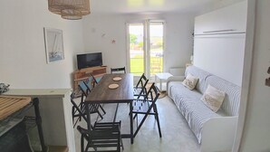 A compact living space with a dining area, a sofa, and a television. - Studio de la plage - Pen Lan (Billiers)