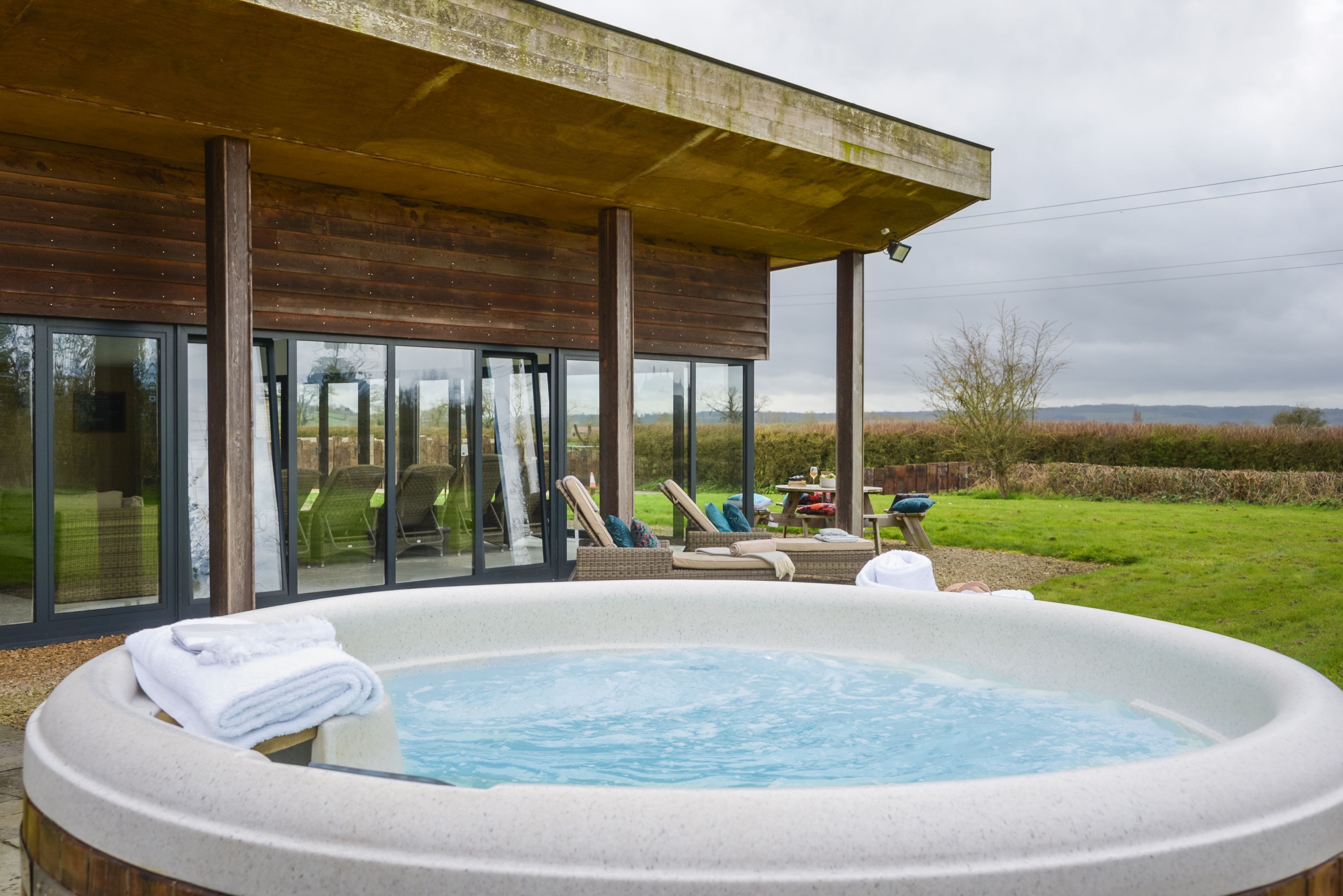 A hot tub area with lounge chairs and a glass-enclosed patio.