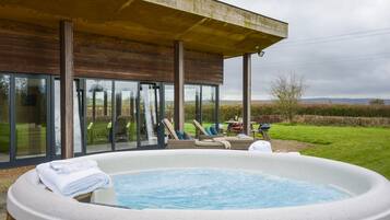 A hot tub area with lounge chairs and a glass-enclosed patio.