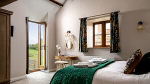 Een slaapkamer met een groot bed, een bureau, een stoel, een raam met gordijnen en uitzicht op de omgeving.