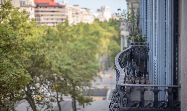Et gadesyn med en bygning, der har en metalbalkon med detaljerede gelændere.