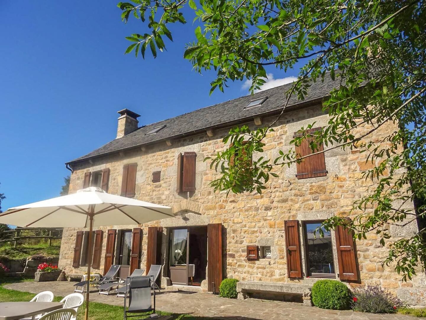 A stone building with a patio area, outdoor seating, and a large umbrella.