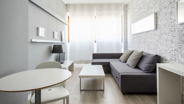 Una sala de estar moderna con un sofá gris, una mesa de centro blanca y un mueble de TV blanco.
