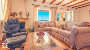 A living room with a leather armchair, a beige sofa, and a glass coffee table with apples. - Villa AZALEA by Abahana Villas (Teulada)