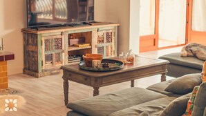 Una sala de estar acogedora con una mesa de centro de madera, un televisor y un sofá.