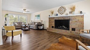 A living room with a fireplace, wooden flooring, and a sofa. - Blue Roof Lodge: Pet-Friendly, Walkable to Downtown Custer (Custer)
