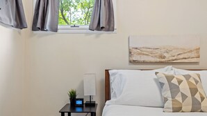 A bedroom with a bed, a nightstand with a lamp, a digital clock, and a painting on the wall. - Blue Roof Lodge: Pet-Friendly, Walkable to Downtown Custer (Custer)