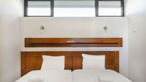 Ein Doppelbett mit Holz-Kopfteil, zwei weiße Kissen und gefaltete weiße Handtücher.