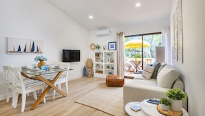 A modern living room with a glass dining table, white sofas, and a large window with a view of the outdoors. - BnBird Sunny Algarve @ Vilamoura (Loulé)