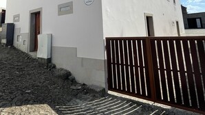 Un edificio blanco con techo de tejas rojas, una puerta de madera y una reja de metal.