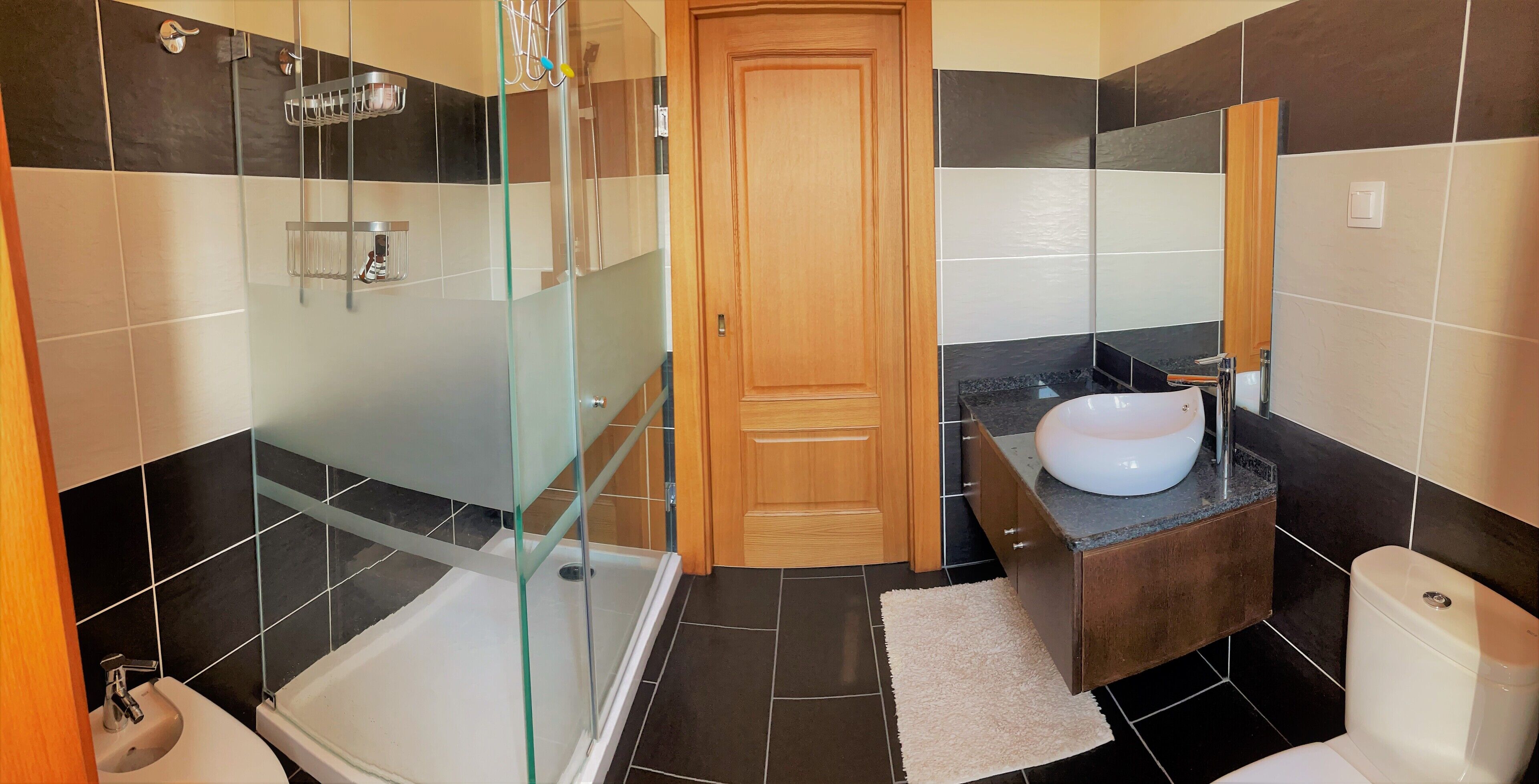 A bathroom with a glass shower enclosure, a bathtub, a sink with a vanity, and a toilet.