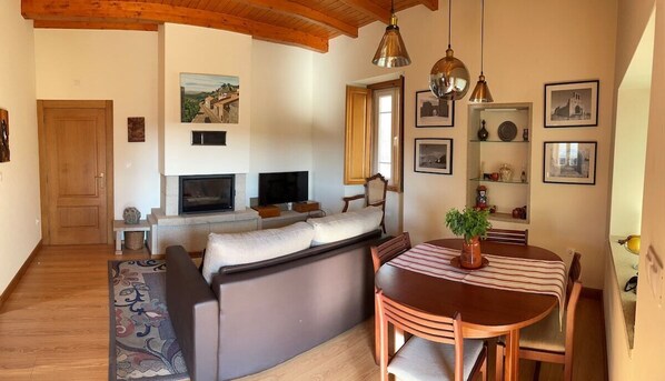 A cozy living room with a fireplace, sofa, TV, and dining area.