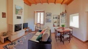 Un salón acogedor con chimenea, un sofá, una mesa de comedor con sillas y un televisor.