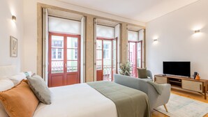Quarto com cama, televisão e vista para varanda.