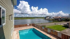 Un quartier résidentiel avec une piscine, une route et une étendue d'eau en arrière-plan.