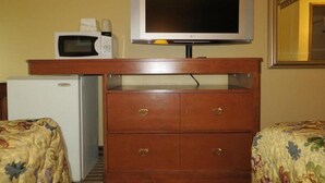 A hotel room with a wooden dresser, a microwave, a small refrigerator, and a television on a stand. - Econo Lodge Expo Center (Portland)