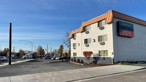 A Portland Inn hotel with a white exterior and a brown roof, located at a busy intersection with visible parking and street signs. - Econo Lodge Expo Center (Portland)