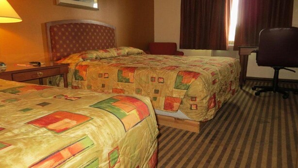 A hotel room with two beds, a desk, a chair, and a window with curtains. - Econo Lodge Expo Center (Portland)