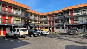 A multi-story motel with a central courtyard, featuring a parking area with several cars. - Econo Lodge Expo Center (Portland)