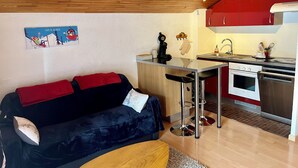 A compact kitchen with a red cabinet, a white oven, and a small dining area.