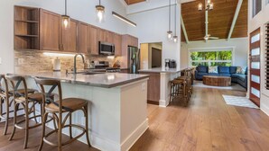 Une cuisine spacieuse avec des meubles en bois, un îlot central doté de tabourets de bar et un coin repas comprenant un canapé et une table basse.