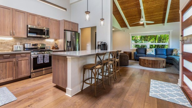 Une cuisine moderne avec des meubles en bois, des appareils en acier inoxydable et un îlot central doté de tabourets de bar.