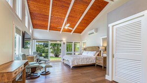 Une chambre spacieuse avec un plafond en bois, un grand lit, un bureau et une chaise.