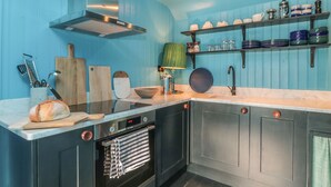 Una cocina moderna con horno empotrado, tabla de madera para cortar y hogaza de pan sobre la encimera.