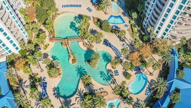 Een resort met meerdere zwembaden, palmbomen en strandgebieden.