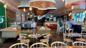 Een modern restaurant met ronde tafels, zachte zitplaatsen en hangende吊灯.