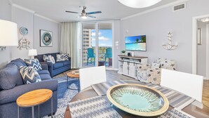 Een moderne woonkamer met een bank, salontafel en televisie. Er is een balkon met uitzicht op de oceaan.