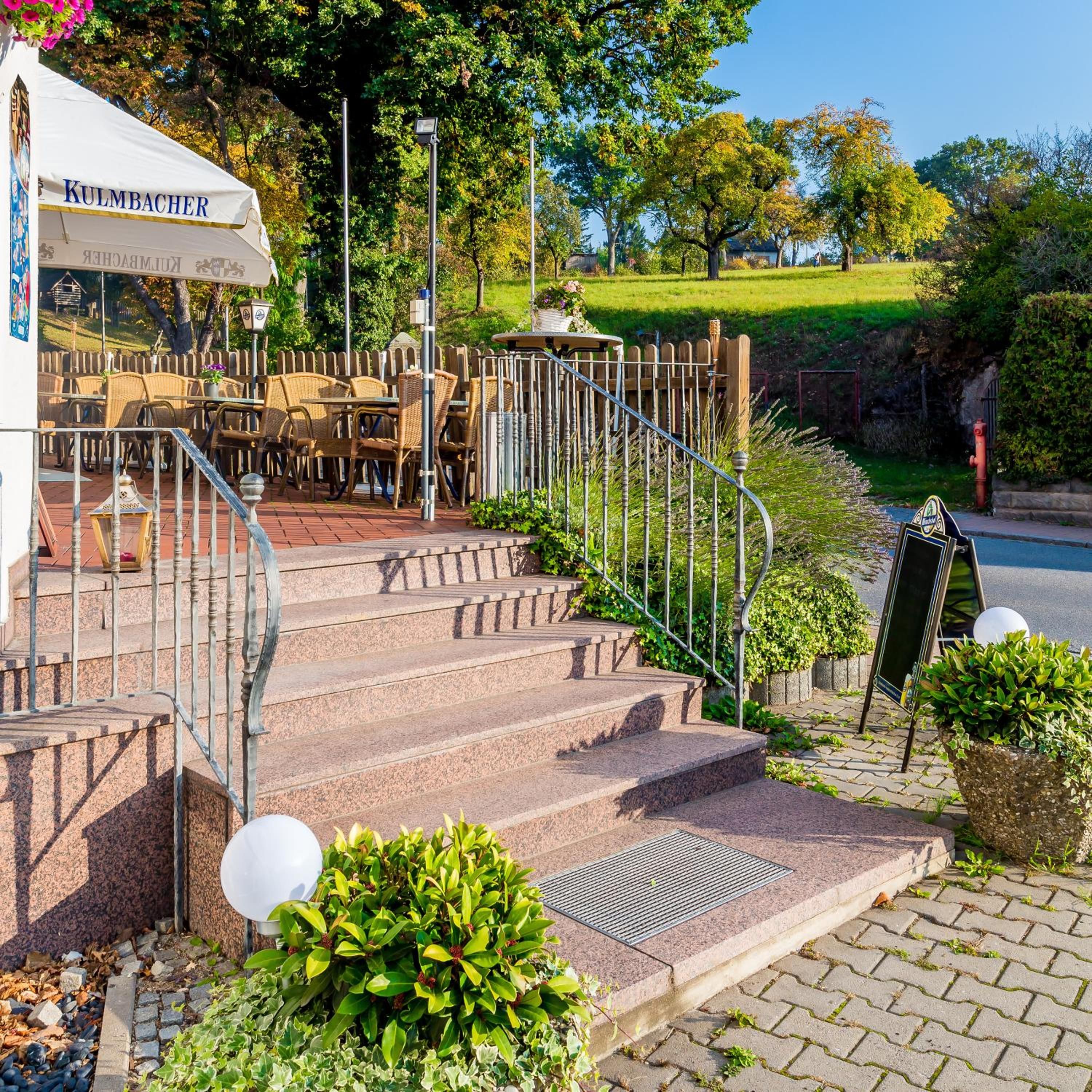 Ein Restaurant mit Außenbereich, einer Treppe zum Eingang und einem Schild.