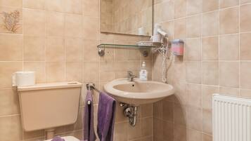 Ein Badezimmer mit Toilette, Waschbecken, Spiegel und Handtuchhalter.