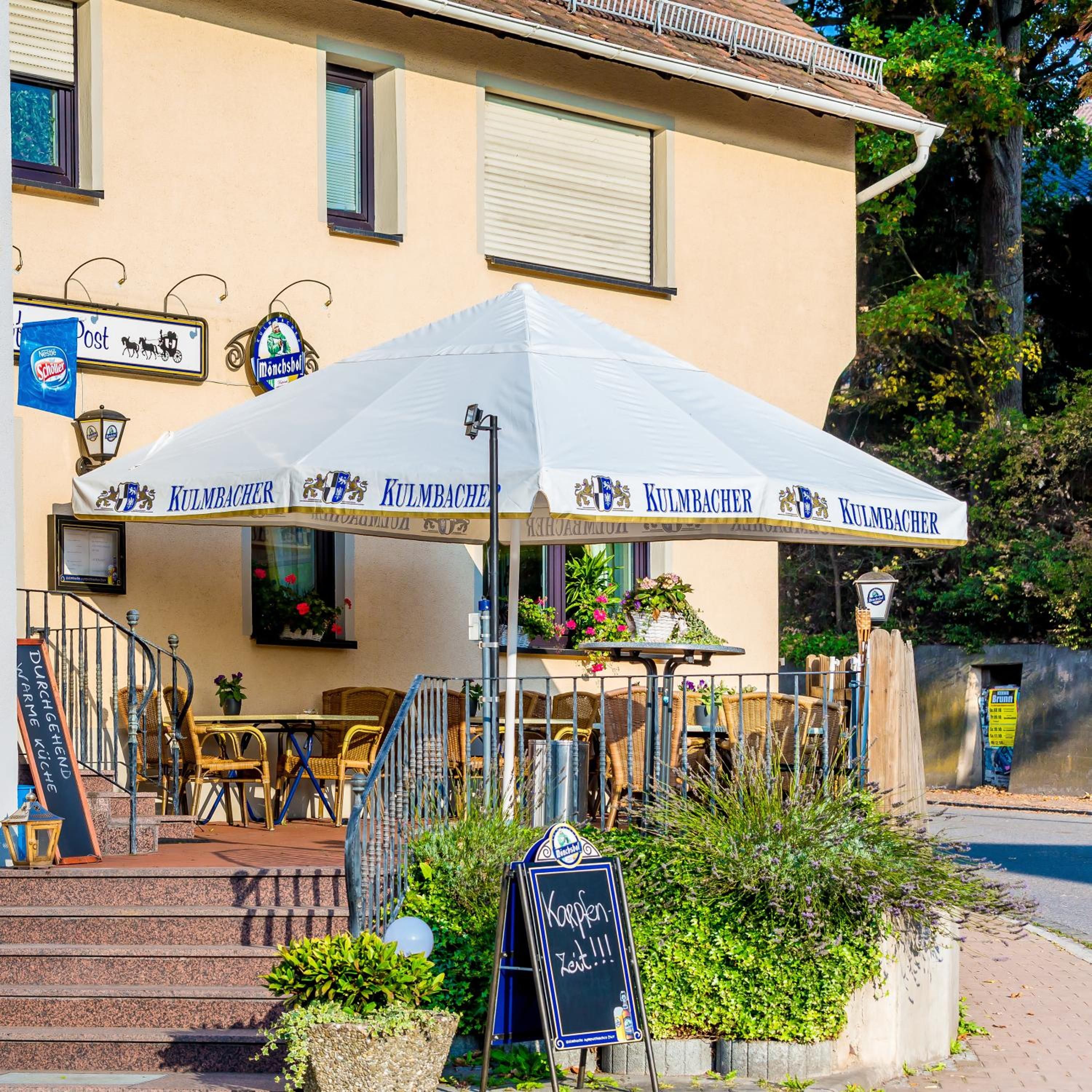A restaurant with outdoor seating, a covered patio, and a sign indicating a special offer.
