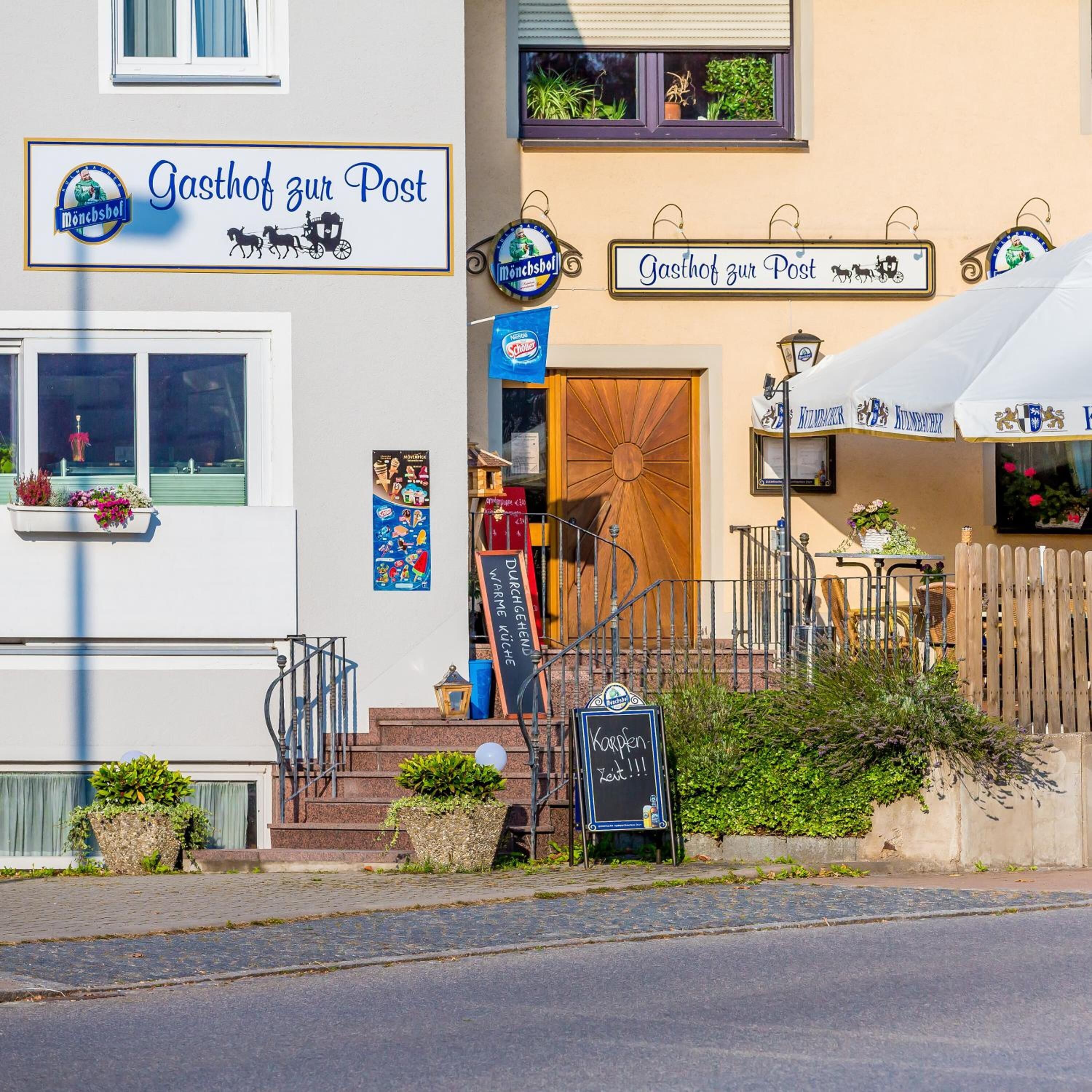Un bâtiment avec une enseigne indiquant « Gasthof zur Post » et une porte en bois.
