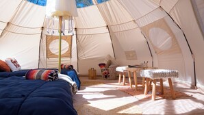 A spacious tent with a bed, a small table, and a basket.